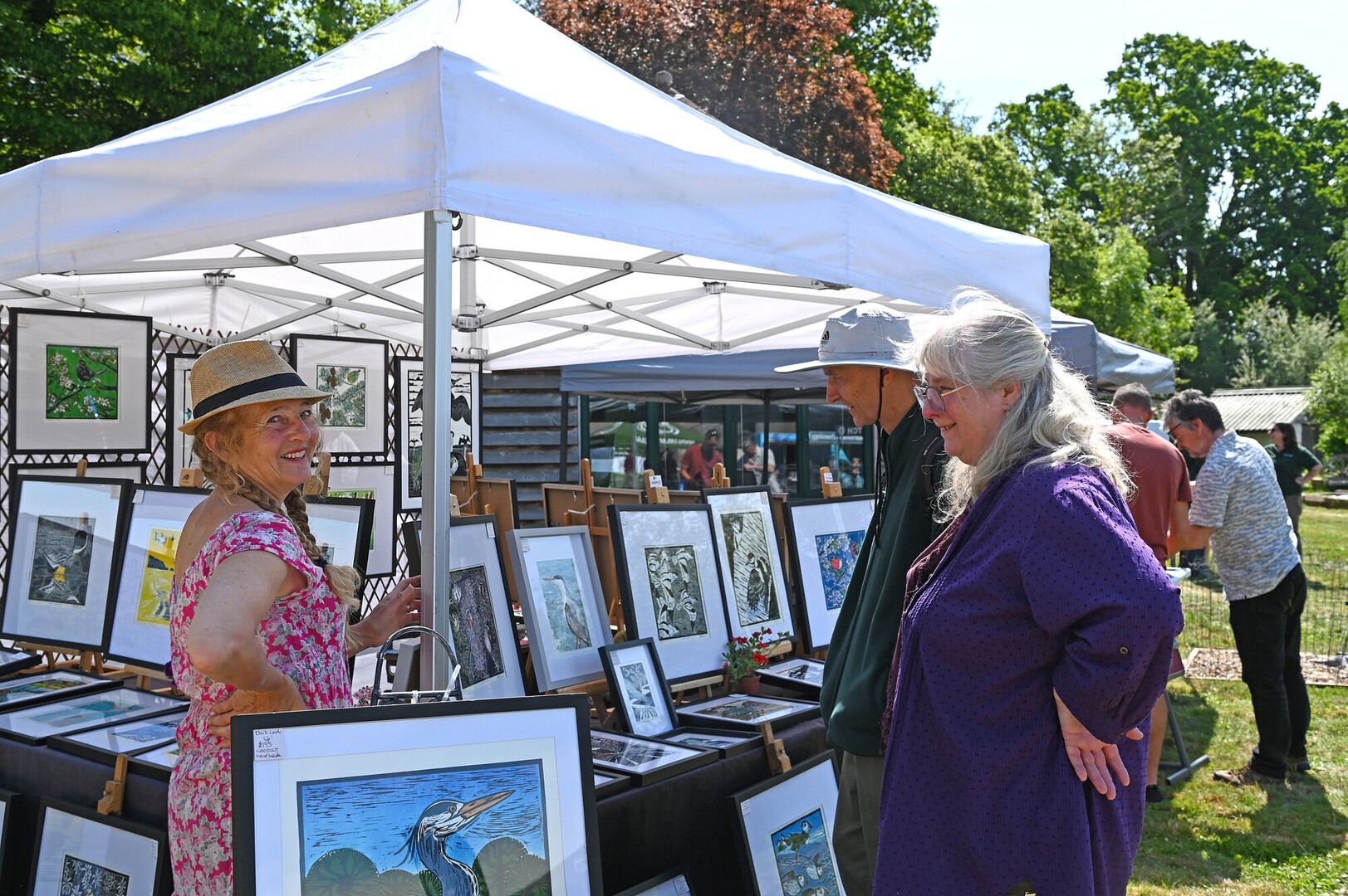 An arts stall at an outdoor fair with people interacting.
