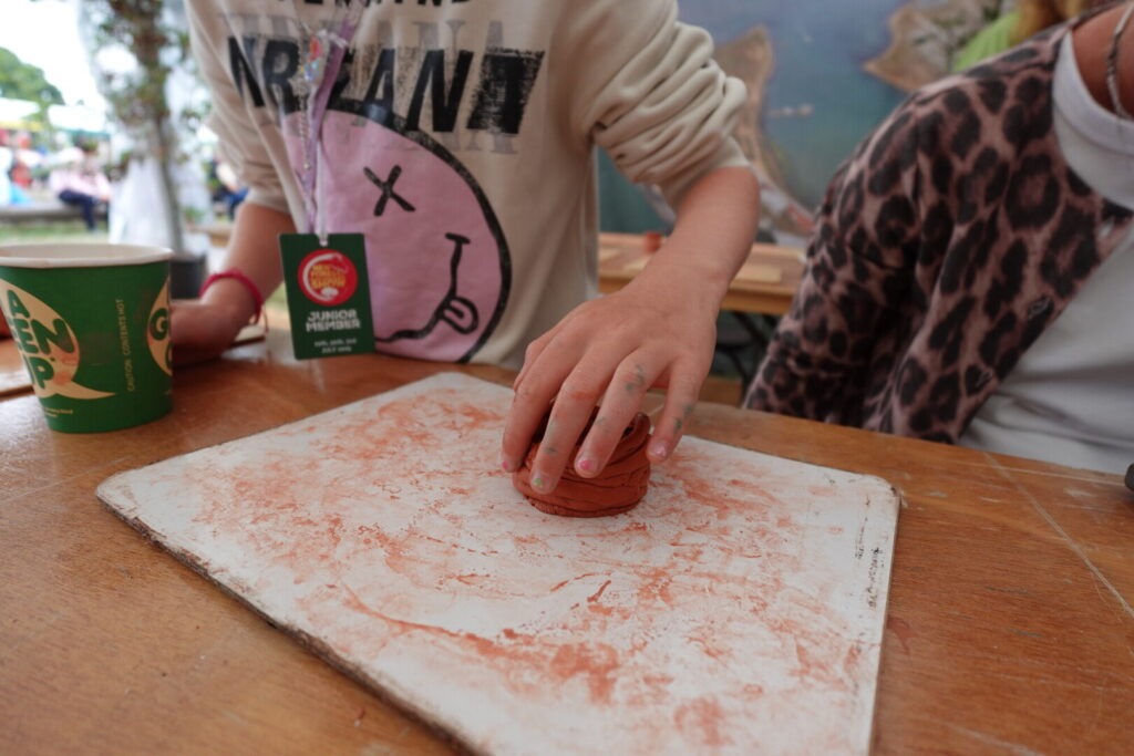 A young person's hands molding clay to make a Roman pot.