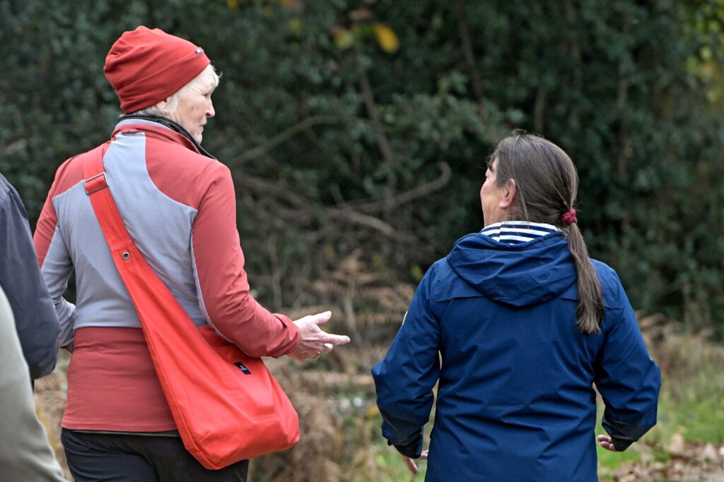 Two walkers talking to each other. One lady is in red and a red hat and the other in blue.