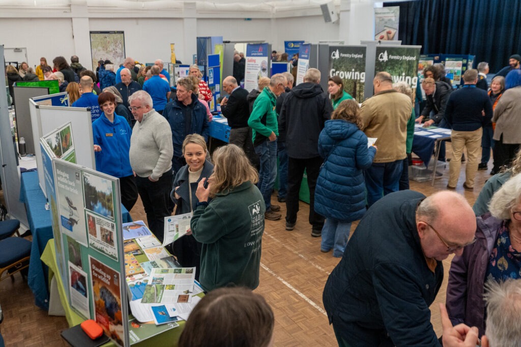 A hall full of stalls and people engaging during a New Forest National Park Volunteer Fair.