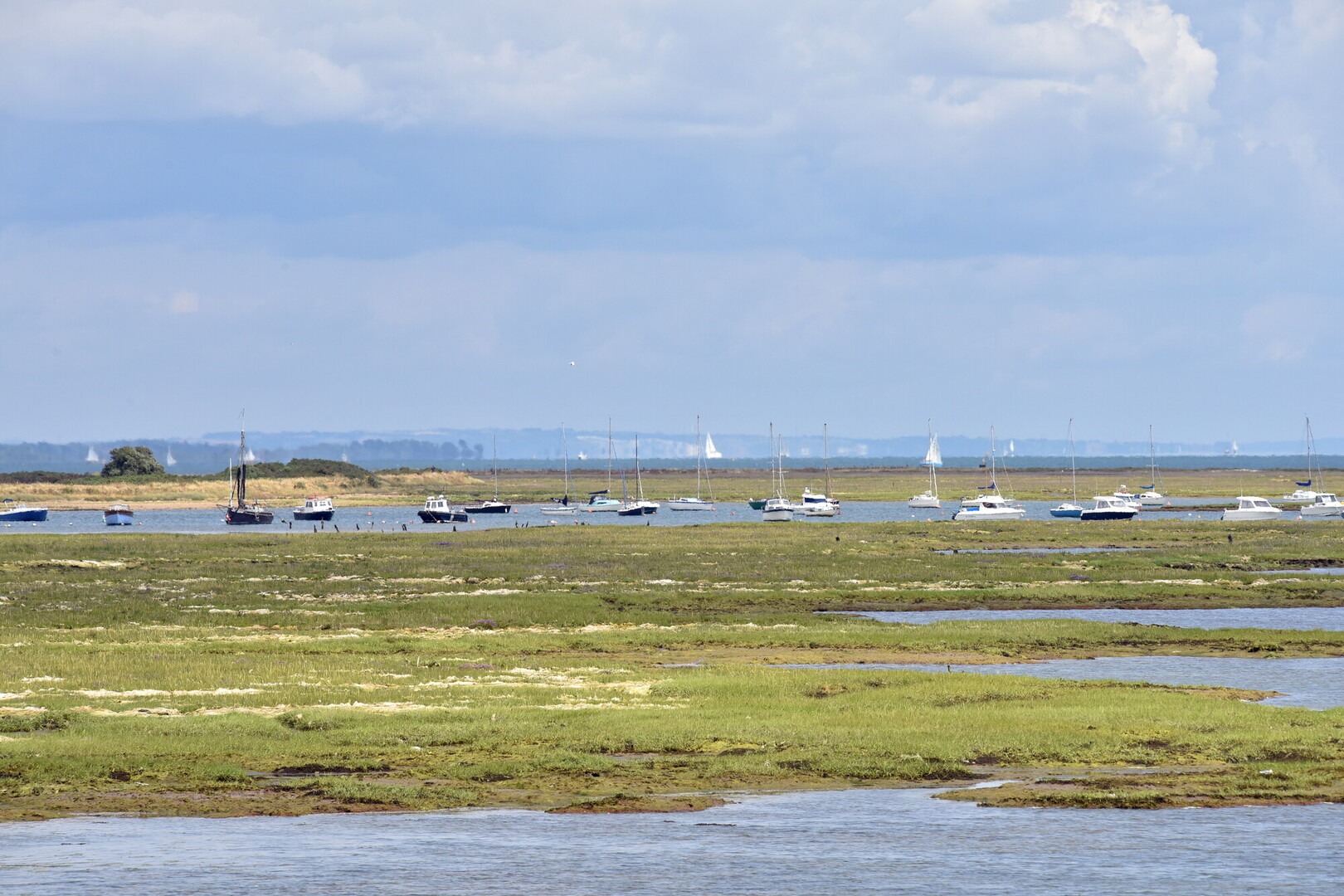 Coastal waters at Keyhaven with a line of moored coats in the background.